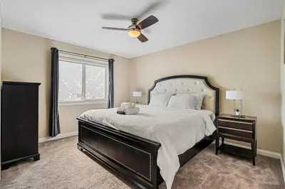 a bedroom with a large bed with a ceiling fan at 5 Bedroom House in McConachie, Near Anthony Henday, Sleeps 12, Backyard, Netflix, Free Parking in Edmonton