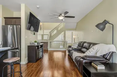 a living room with a leather couch and a staircase at 5 Bedroom House in McConachie, Near Anthony Henday, Sleeps 12, Backyard, Netflix, Free Parking in Edmonton