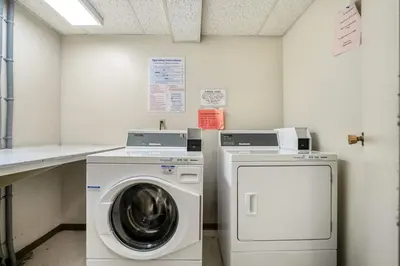 a laundry room with a washing machine and a washer at Prime Location Near Jasper Ave with Downtown Views, Netflix, Gym, Sauna, Sleeps 4 in Edmonton