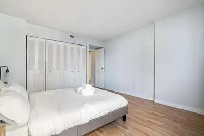 a white bedroom with a large bed with white sheets at Prime Location Near Jasper Ave with Downtown Views, Netflix, Gym, Sauna, Sleeps 4 in Edmonton