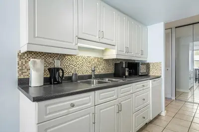 a kitchen with white cabinets and a sink at Prime Location Near Jasper Ave with Downtown Views, Netflix, Gym, Sauna, Sleeps 4 in Edmonton