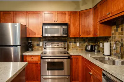 a kitchen with wooden cabinets and stainless steel appliances at 3BR in Wintergreen, Family Sized, Wood Burning Fireplace, Secure Parking, Ski Hill Bus Access in Whistler
