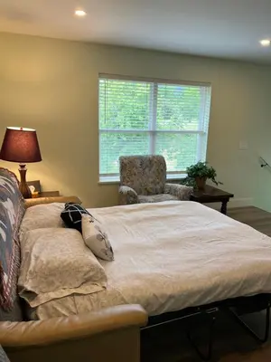 a bedroom with a bed and a chair and a window at Wellington House in Nanaimo