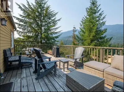 a deck with chairs and a couch and a grill at 1BR plus Loft in Gondola Village, Creekside, Amazing Patio with Views, Near Gondola, Free Parking in Whistler