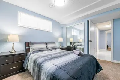a bedroom with a large bed with blue walls at Cozy Suite - Walk to West Ed Mall in Edmonton