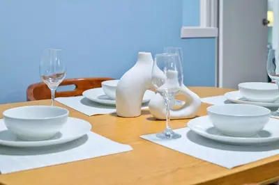a wooden table with white dishes and wine glasses at Cozy Suite - Walk to West Ed Mall in Edmonton