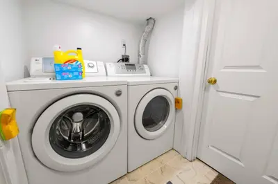 a white washing machine in a white laundry room at Cozy Suite - Walk to West Ed Mall in Edmonton