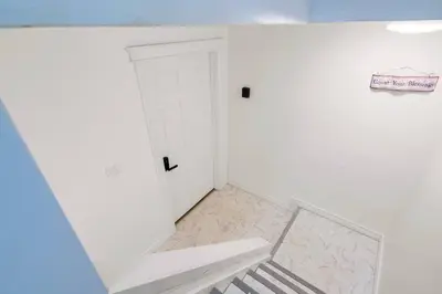a white room with a white door and a staircase at Cozy Suite - Walk to West Ed Mall in Edmonton