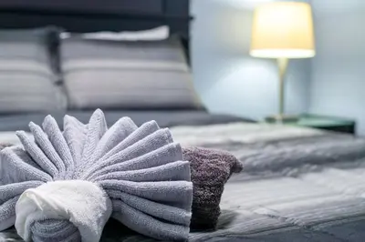 a towel sitting on a bed next to a lamp at Cozy Suite - Walk to West Ed Mall in Edmonton