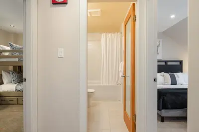 a hallway leading to a bedroom with a bed and a bathroom at 1BR plus Two Dens in The Gables, Epic Location Near Gondolas, Private Balcony, Fireplace, Parking in Whistler