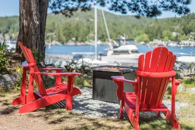 two red chairs and a table next to a tree at John Henry's Marina and Resort in Garden Bay