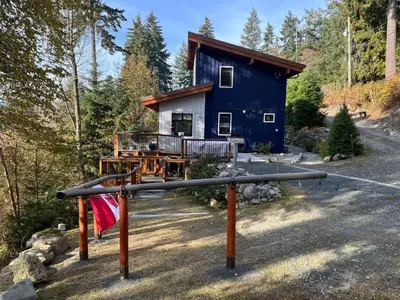 a blue house in the middle of a forest at Along the Way in Youbou