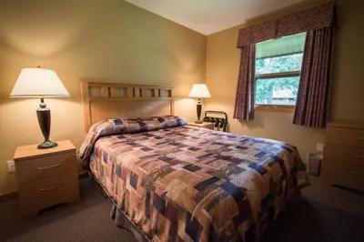 a bedroom with a bed and a lamp and a window at Alpine Meadows Resort in Clearwater