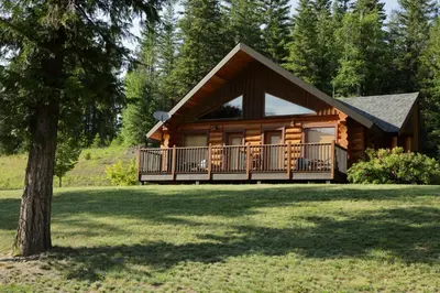a log cabin with a balcony and a tree at Alpine Meadows Resort in Clearwater