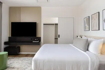 a bedroom with a white bed and a flat screen tv at Smithe House in Vancouver