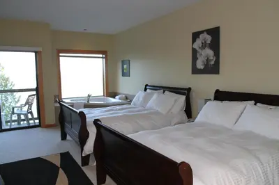 a bedroom with two beds and a bathroom with a sink at Moon Water Lodge in Malahat