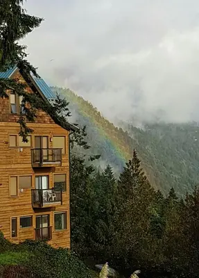 a rainbow in the mountains next to a building at Moon Water Lodge in Malahat