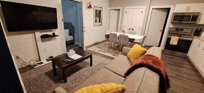 a living room with a couch and a tv and a table at Two Bedroom Suite with AC, Sleeps 8- Welcome Snacks and Drinks Included in Langford