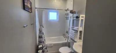 a white bathroom with a shower and a toilet at Two Bedroom Suite with AC, Sleeps 8- Welcome Snacks and Drinks Included in Langford