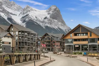 a street in a town with a mountain in the background at New Spacious Mountain View Condo in Canmore With Hot Tub, Park Pass, Prime Location in Canmore