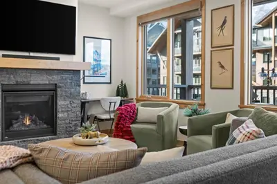 a living room with a couch and a fireplace at New Spacious Mountain View Condo in Canmore With Hot Tub, Park Pass, Prime Location in Canmore