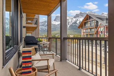 a balcony with chairs and a view of mountains at New Spacious Mountain View Condo in Canmore With Hot Tub, Park Pass, Prime Location in Canmore