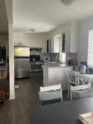 a kitchen with stainless steel appliances and wooden floors at Quiet-comfy 4 bedroom house on a quiet tree lined street in Kitsilano in Vancouver