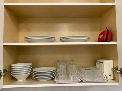 a shelf with plates and bowls and glasses at Two Bedroom Suite Burnaby Metrotown in Burnaby