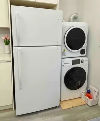 a microwave sitting on top of a white refrigerator at Two Bedroom Suite Burnaby Metrotown in Burnaby