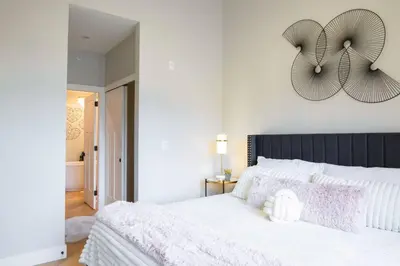 a bedroom with a white bed with a clock on the wall at Brand New Penthouse with Lake and Mtn Views in Harrison Hot Springs