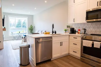 a kitchen with white cabinets and stainless steel appliances at New 1 Bed Condo with Mtn Views in Harrison Hot Springs