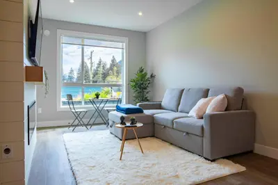 a living room with a couch and a large window at New 1 Bed Condo with Mtn Views in Harrison Hot Springs