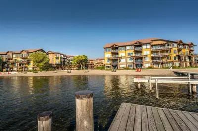 a row of apartment buildings next to a body of water at Condo at Barona Beach Lakeside Resort in West Kelowna
