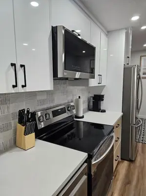 a kitchen with white cabinets and a stove top oven at Cozy 2 bedrooms and 1 bath for 4 guests! in Calgary
