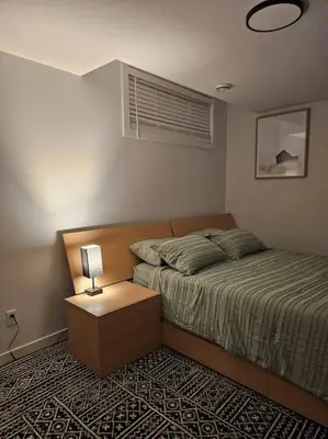 a bedroom with a bed and a table with a lamp at Cozy 2 bedrooms and 1 bath for 4 guests! in Calgary