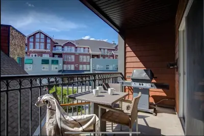 a patio with a table and a grill on a balcony at Cozy One Bedroom Condo with Indoor Pool and HotTub in Canmore