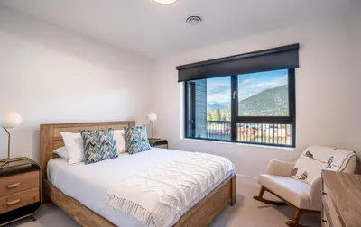 a bedroom with a bed and a window and a chair at Drop in Condo by Revelstoke Vacations in Revelstoke