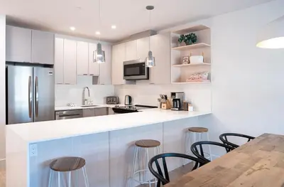 a kitchen with white cabinets and a table with stools at Drop in Condo by Revelstoke Vacations in Revelstoke