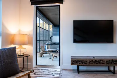 a living room with a flat screen tv and a piano at Drop in Condo by Revelstoke Vacations in Revelstoke