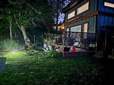 a house with a porch and a yard with plants at Tiny House with Hot Tub, close to golf and skiing!! in Oyster Bay