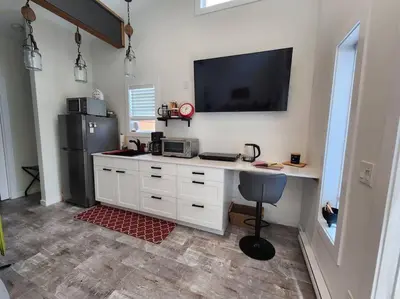 a kitchen with a desk with a television and a refrigerator at Tiny House with Hot Tub, close to golf and skiing!! in Oyster Bay