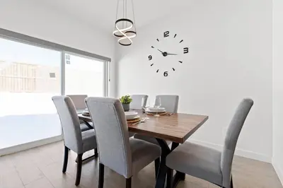 a dining room with a table and a clock on the wall at Family Home Retreat - 9 mins to WEM - Vintage Arcade-Ping Pong -Air Conditioning in Edmonton