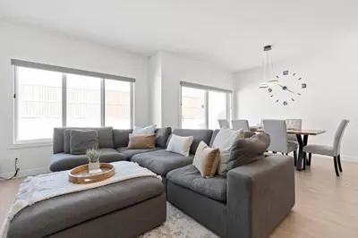 a living room with a gray couch and a table at Family Home Retreat - 9 mins to WEM - Vintage Arcade-Ping Pong -Air Conditioning in Edmonton