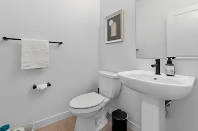 a white bathroom with a toilet and a sink at Family Home Retreat - 9 mins to WEM - Vintage Arcade-Ping Pong -Air Conditioning in Edmonton