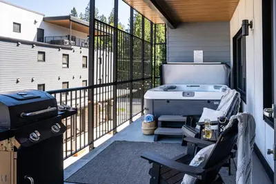 a screened in porch with a hot tub and a grill at Birdies and Bears by Revelstoke Vacations in Revelstoke