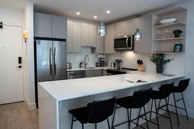 a kitchen with a large white counter with bar stools at Birdies and Bears by Revelstoke Vacations in Revelstoke