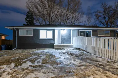 a house with a white fence in the snow at Centre Street 2bed Upper Suite - 4408 in Calgary