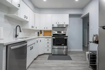 a kitchen with white cabinets and stainless steel appliances at Centre Street 2bed Upper Suite - 4408 in Calgary