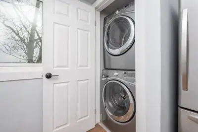 a laundry room with two washing machines and a white door at Centre Street 2bed Upper Suite - 4408 in Calgary