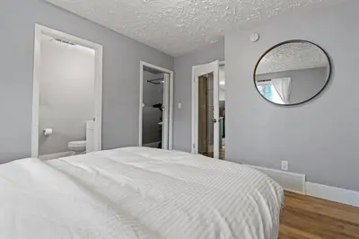 a white bedroom with a bed and a mirror at Elegant Boho Retreat - 8 min to WEM in Edmonton